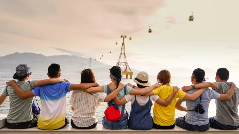 A group of people with their arm on the next one's shoulders, showing group harmony.