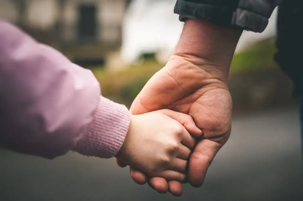 Parent holding child's hand, symbolizing inheritance, family protection, and legacy