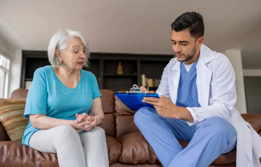 Senior woman with medical caregiver reviewing documents for Medicaid and long-term care.